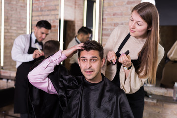 Unpleasantly surprised man with regretting woman hairdresser in salon