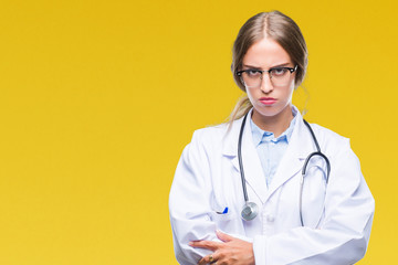 Beautiful young blonde doctor woman wearing medical uniform over isolated background skeptic and nervous, disapproving expression on face with crossed arms. Negative person.