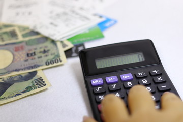 計算機で計算する人と紙幣とクレジットカードと領収書	