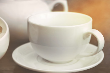 White empty porcelain mug and ceramic teapot in cafe in sunlight. Template glass kitchenware for designer use