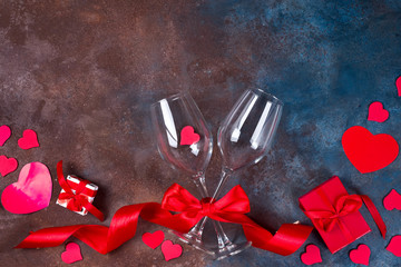 Two glass of wine, hearts and gift box on stone background. Romantic still life. Valentine's Day with copy space, flat lay.