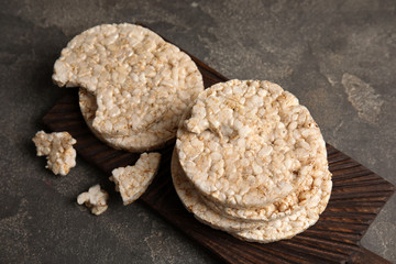 Wooden board with crunchy rice cakes on table