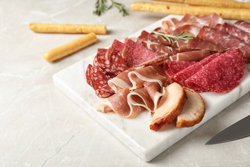 Cutting board with different meat delicacies on gray table