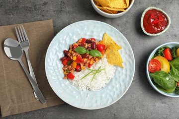 Tasty chili con carne served with rice on gray table, flat lay