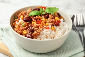 Gardinen Chilischoten Tasty chili con carne served with rice in bowl on table  © New Africa