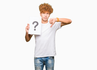 Young handsome man holding paper with question mark with angry face, negative sign showing dislike...