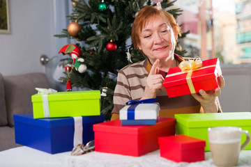 Obraz na płótnie Canvas Happy elderly woman opens christmas gift boxes
