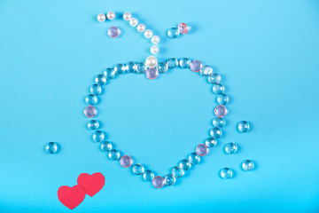 Heart on a blue background lined with white and pink beads and stones.