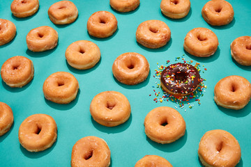 chocolate frosted donut in a lineup of glazed donuts