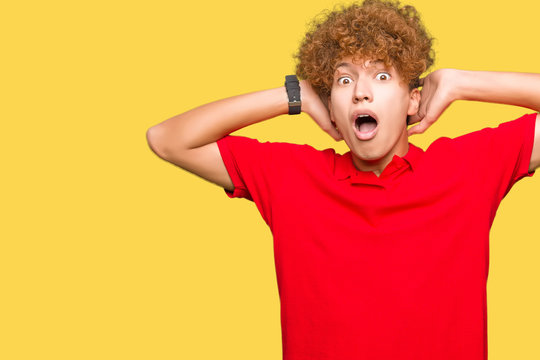Young handsome man with afro hair wearing red t-shirt Crazy and scared with hands on head, afraid and surprised of shock with open mouth
