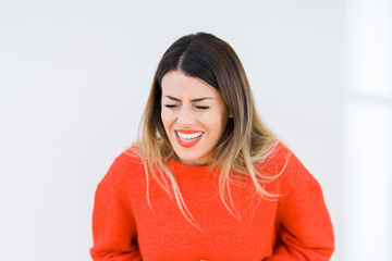 Young woman wearing casual red sweater over isolated background with hand on stomach because nausea, painful disease feeling unwell. Ache concept.