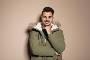 Young man wearing warm clothes on color background. Ready for winter vacation