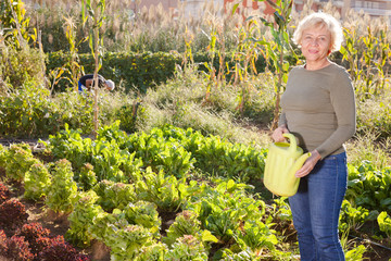 Woman posing with watering can in garden