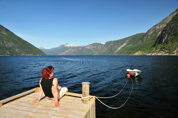 Frau sitzt am Hardangerfjord
