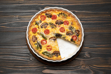 Baked homemade quiche pie in ceramic baking form on concrete background