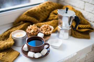 Warm home arrangement on windowsill, coffee and cookies with can