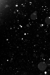 a bokeh of white snow on a black background