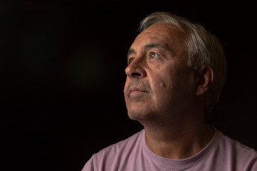 Dark portrait image of a mature man, with copy space 