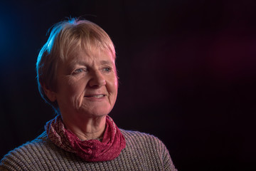Portrait image of a happy mature woman on a black background, taken with copy space 