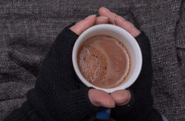 Mature Caucasian hands holding a hot drink 