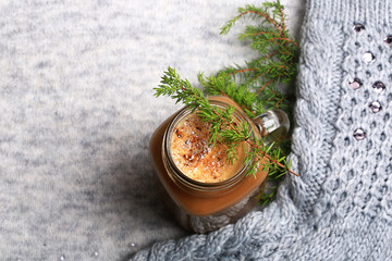 Fototapeta na wymiar Christmas winter coffee with a spruce branch on a knitted gray background
