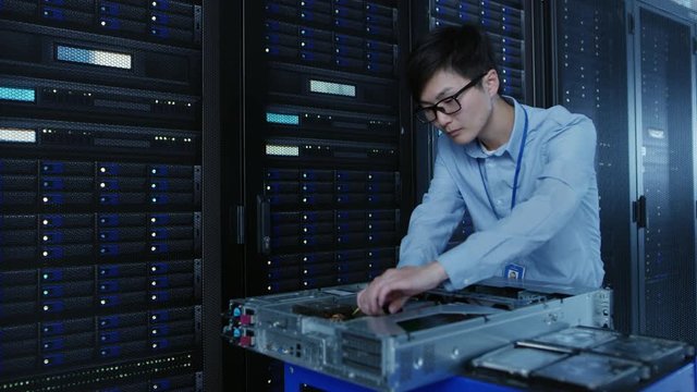 In the Modern Data Center: IT Technician Working with Server Racks, on a Pushcart Installing New Hardware. Engineer Doing Maintenance and Diagnostics of the Database.