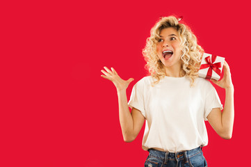 girl with a white gift in her hands on a red isolated background in full growth.Concept for lovers day, Valentine's Day concept