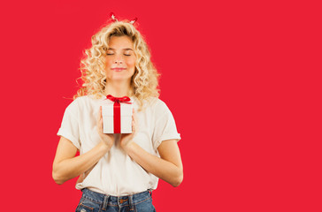 girl with a white gift in her hands on a red isolated background in full growth.Concept for lovers day, Valentine's Day concept