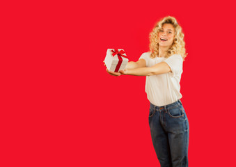 girl with a white gift in her hands on a red isolated background in full growth.Concept for lovers day, Valentine's Day concept