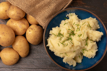 bowl of mash potato topped with chives and a sack of whole potatoes 