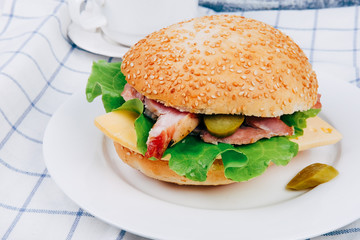 Tasty European snack hamburger sesame bun with ham and coffee