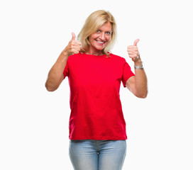 Fototapeta na wymiar Middle age blonde woman over isolated background success sign doing positive gesture with hand, thumbs up smiling and happy. Looking at the camera with cheerful expression, winner gesture.