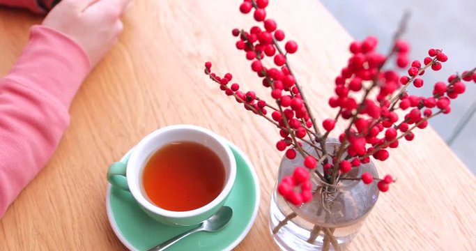 Red tea in green cup with teapot and red flowers in background. Man working near. 4K Footage - Video