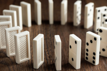 Creative background, white domino, on brown wooden background. Concept of domino effect, chain...