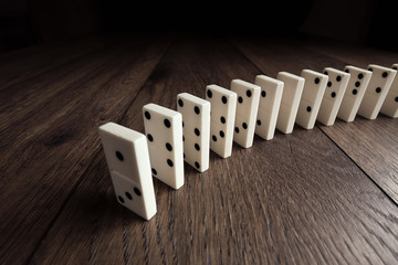 Creative background, white domino, on brown wooden background. Concept of domino effect, chain...