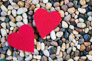 Two red decorative hearts and gray sea pebbles. Valentine's Day Concept.
