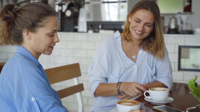 Lesbian couple having date in cafe. Beautiful girls talking while drinking coffee.