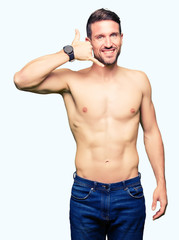 Handsome shirtless man showing nude chest smiling doing phone gesture with hand and fingers like talking on the telephone. Communicating concepts.