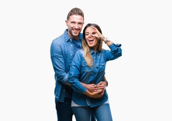 Young couple in love over isolated background doing ok gesture with hand smiling, eye looking through fingers with happy face.