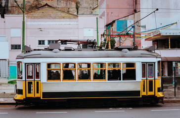 Fototapeta na wymiar Famous old historic tourist yellow street tram in Lisbon. Famous vintage tourist travel attraction. Colorful architecture city buildings street scene, Portugal