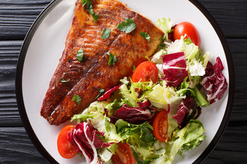 Spicy baked pike fillet and fresh vegetable salad close-up on a plate. horizontal top view