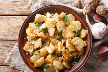 Spicy fried Jerusalem artichoke with garlic, cheese and parsley closeup on a plate. horizontal top view