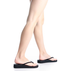 Woman legs in black flip flops goes on white background isolation