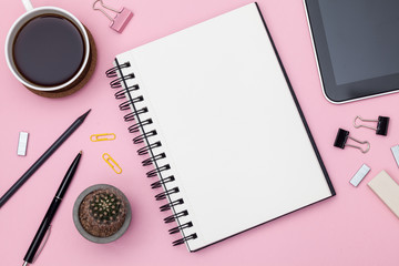 Top view workspace mockup on pink background with notebook, cactus, pen, pencil, cup of coffee, clips and accessories. Mockup