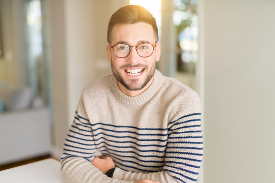 Young handsome man wearing glasses at home with a happy and cool smile on face. Lucky person.