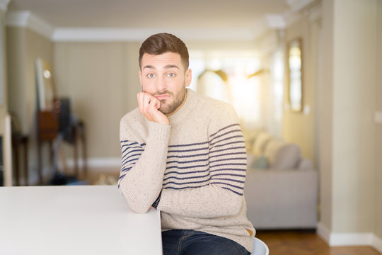 Young handsome man wearing a sweater at home thinking looking tired and bored with depression problems with crossed arms.