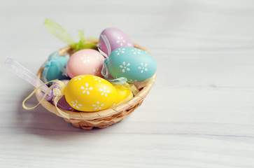 Easter Eggs in nest. Basket of colorful easter eggs on wooden table with free copy space for your text