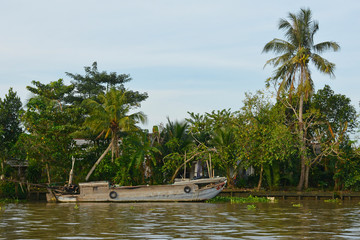 An old wooden boat moored at the side of a waterway outside the city of Can Tho in the Vietnam Mekong Delta