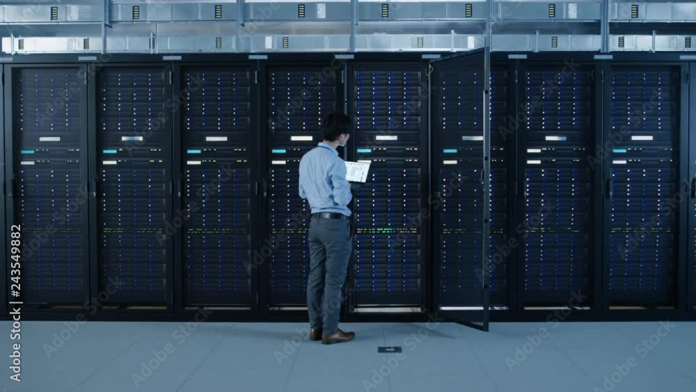 Aufkleber in the modern data center: it engineer standing beside open server rack cabinets, does wireless main