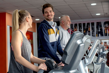 Smiling people running on a treadmill in the health club